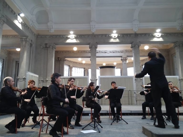 José Escandell dirigiendo una orquesta de cámara en un salón clásico